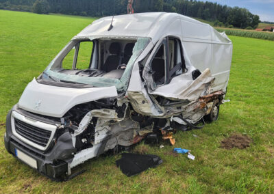 Schwer beschädigter Kleintransporter in einer Wiese.