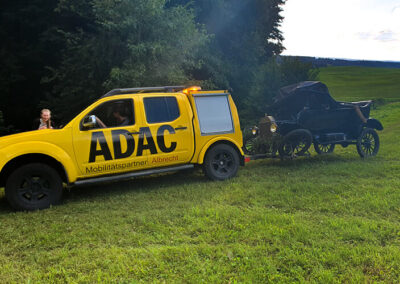Schwer beschädigter schwarzer Oldtimer wird von ADAC-Fahrzeug abgeschleppt.