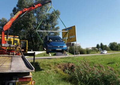 Blaues Auto wird mit einem Kran auf einen ADAC-Abschlepp-LKW geladen.